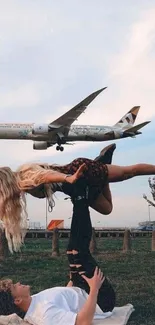 Couple doing acroyoga with airplane overhead at sunset.