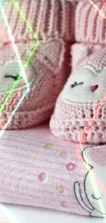 Pink baby booties on stacked baby clothes, cozy and cute design.