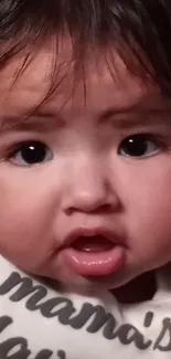 Close-up of an adorable baby with expressive eyes and chubby cheeks.