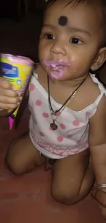 Smiling baby enjoying ice cream, sitting on a colorful mat.