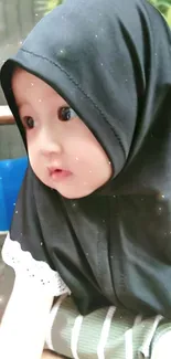 Adorable baby with black scarf gazes softly.