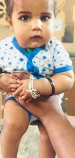 Adorable baby in a blue star-patterned outfit.