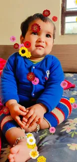 Smiling baby in blue sweater on bed.