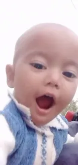 Adorable baby in blue sweater, smiling at the camera.