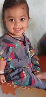 Adorable baby in a colorful outfit sitting and smiling.