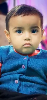 Adorable baby in colorful blue and red outfit.