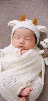 Baby sleeping in animal-themed outfit with a small teddy bear.