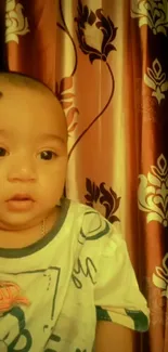 Adorable baby in front of a copper floral curtain wallpaper.