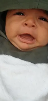 Adorable baby in a green hoodie with a cute expression.