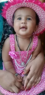 Adorable baby in pink dress with hat smiling.