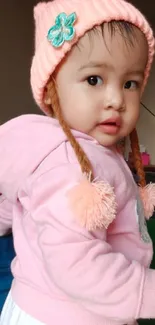 Adorable baby in pink outfit with cute hat.