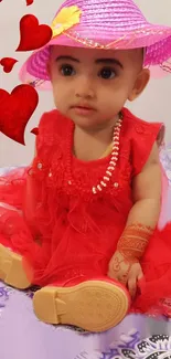 Adorable baby in red dress with pink hat and hearts around.