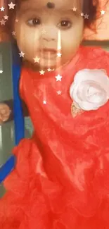 Adorable baby wearing a red dress with a flower detail.