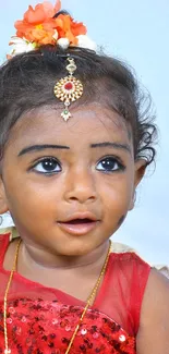 Adorable baby in red dress with floral hair accessory.