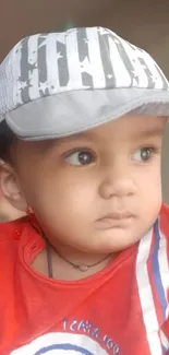 Adorable baby in red shirt with cap.