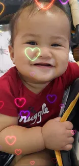 Smiling baby sitting in stroller with red shirt.