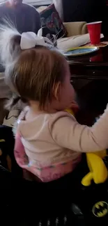 Baby girl plays in toy car with bow.