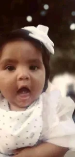 Cute baby with white bow smiling cheerfully.