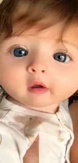 Close-up of a cute baby with blue eyes and brown hair.