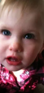 Adorable baby with blue eyes and pink outfit close-up.