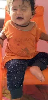 Adorable baby smiling on an orange chair.