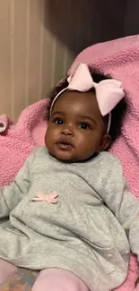 Adorable baby girl with pink bow on blanket.