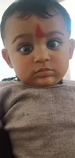 Adorable baby with expressive eyes and soft tone background.