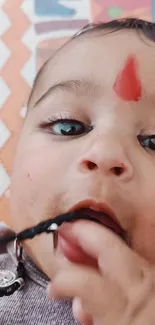 Cute baby with bindi playing for wallpaper.