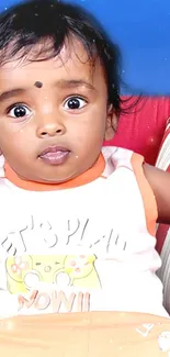 Adorable baby with big eyes on blue sofa.