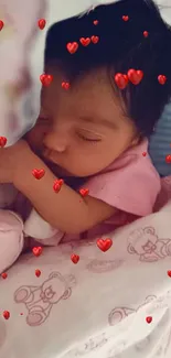 Baby sleeps surrounded by small red hearts, wearing a pink outfit.