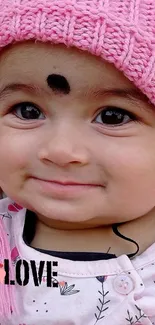 Adorable baby wearing a pink knitted hat with a lovely smile.