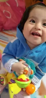 Adorable baby in blue smiling with toys.