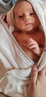 Adorable baby wrapped in a soft towel, showcasing innocence and warmth.