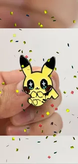 Hand holding cute yellow cartoon character with confetti.