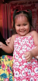 Smiling toddler in a red floral dress for mobile wallpaper.