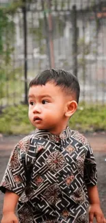 Adorable child in patterned shirt outdoors, exuding charm.