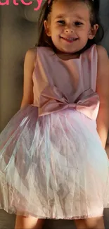 Young girl smiling in a pink dress with a beautiful bow.