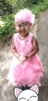 A smiling child in a pink dress on a country path with greenery.