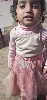 Adorable child in a pink dress outdoors.