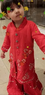 Child in a bright red outfit standing indoors.