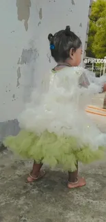 Child wearing fluffy tutu dress outdoors.