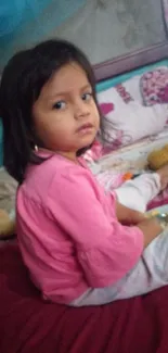 Adorable child sitting on a cozy bed with toys.