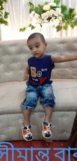 Adorable child sitting on a beige sofa with floral decor.