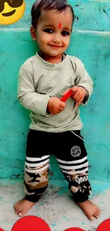 Adorable child smiling in casual outfit against turquoise wall.