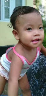 Adorable child leaning on a chair outdoors, smiling with a colorful outfit.