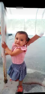 Smiling young girl holding a pole outdoors.