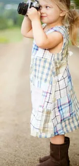 Child with vintage camera in a field.