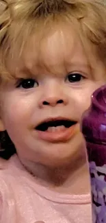 Cute toddler smiling with a purple toy.