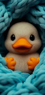 Cute duck toy nestled in a blue knitted blanket.