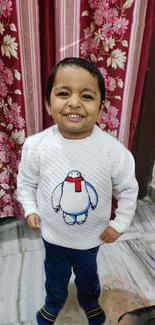 Smiling child in white sweater with floral background.